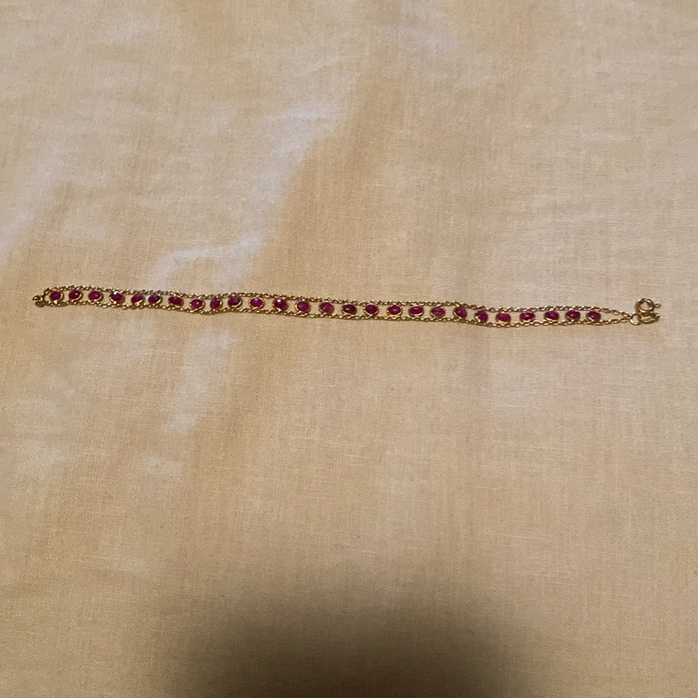 Delicate gold bracelet with ruby red colour beads.